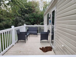 Eine überdachte Terrasse im Freien mit weißer Brüstung, einem Tisch mit Stühlen und einem braunen Teppich.
