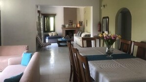 A living room with a sofa, a dining table with chairs, and a fireplace. - Terpsichori Hotel (Chania)