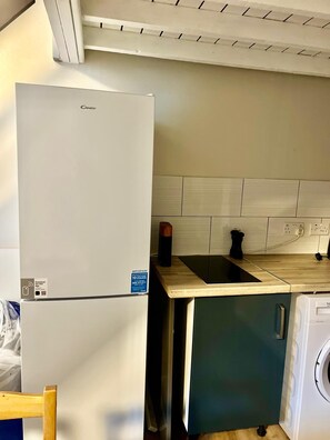 A compact kitchen with a white refrigerator, a sink, and a washing machine. - Apartment Sleeps 4 near Station (Purley)
