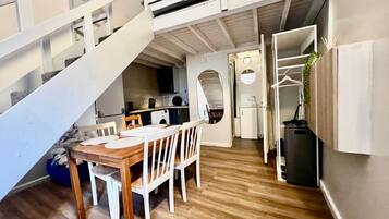 A compact living space with a dining area, kitchen, and a staircase leading to an upper level.