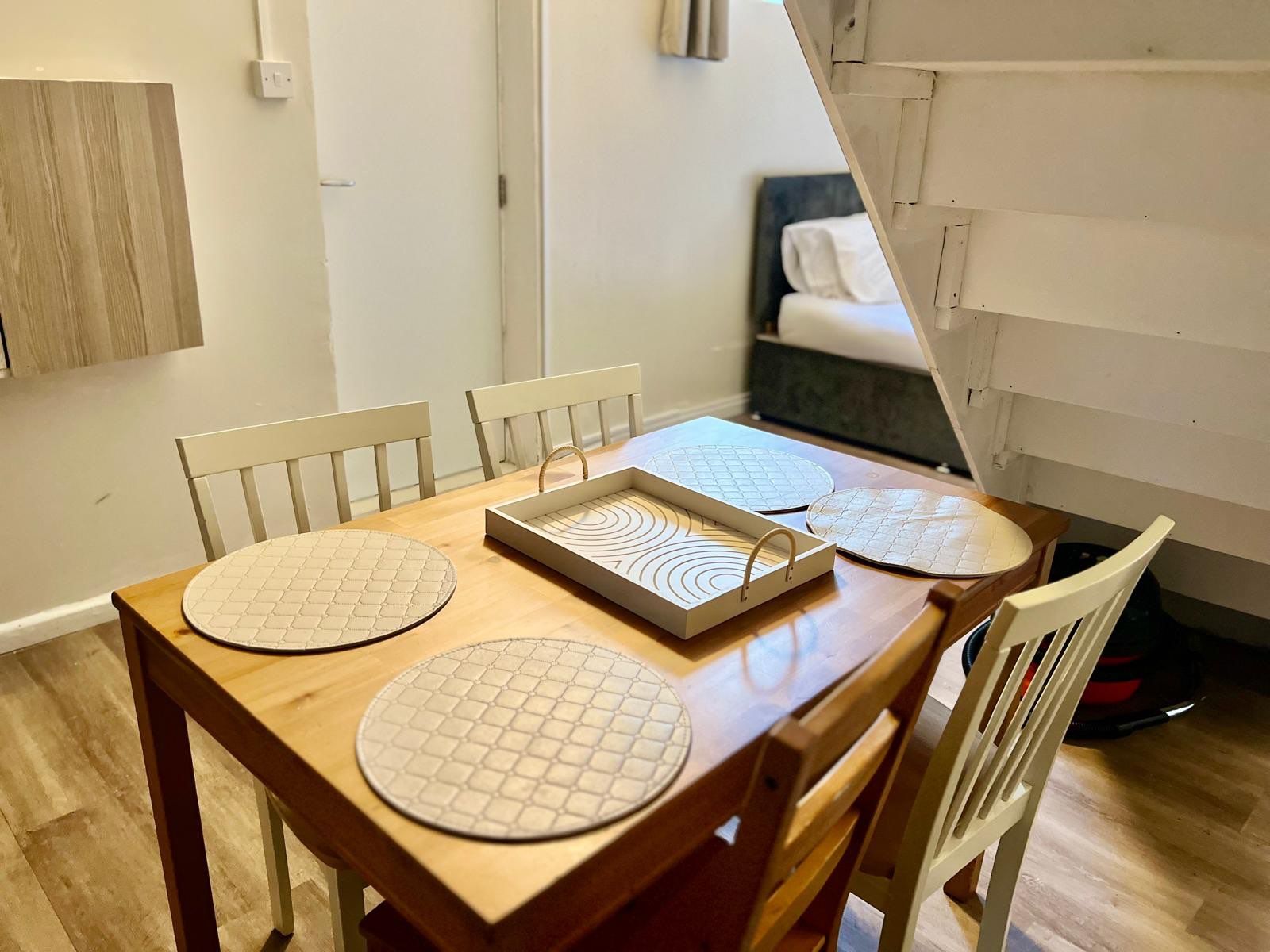 A dining area with a wooden table, four chairs, and a tray with circular placemats.