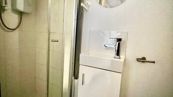 A bathroom with a glass-enclosed shower, a sink with a mirror above it, and a toilet.