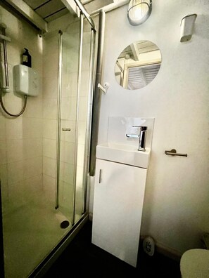 A bathroom with a glass-enclosed shower, a sink with a mirror above it, and a toilet. - Apartment Sleeps 4 near Station (Purley)