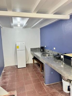 Eine kleine Küche mit einem weißen Kühlschrank, einer Edelstahl-Arbeitsfläche und einem Spülbecken.