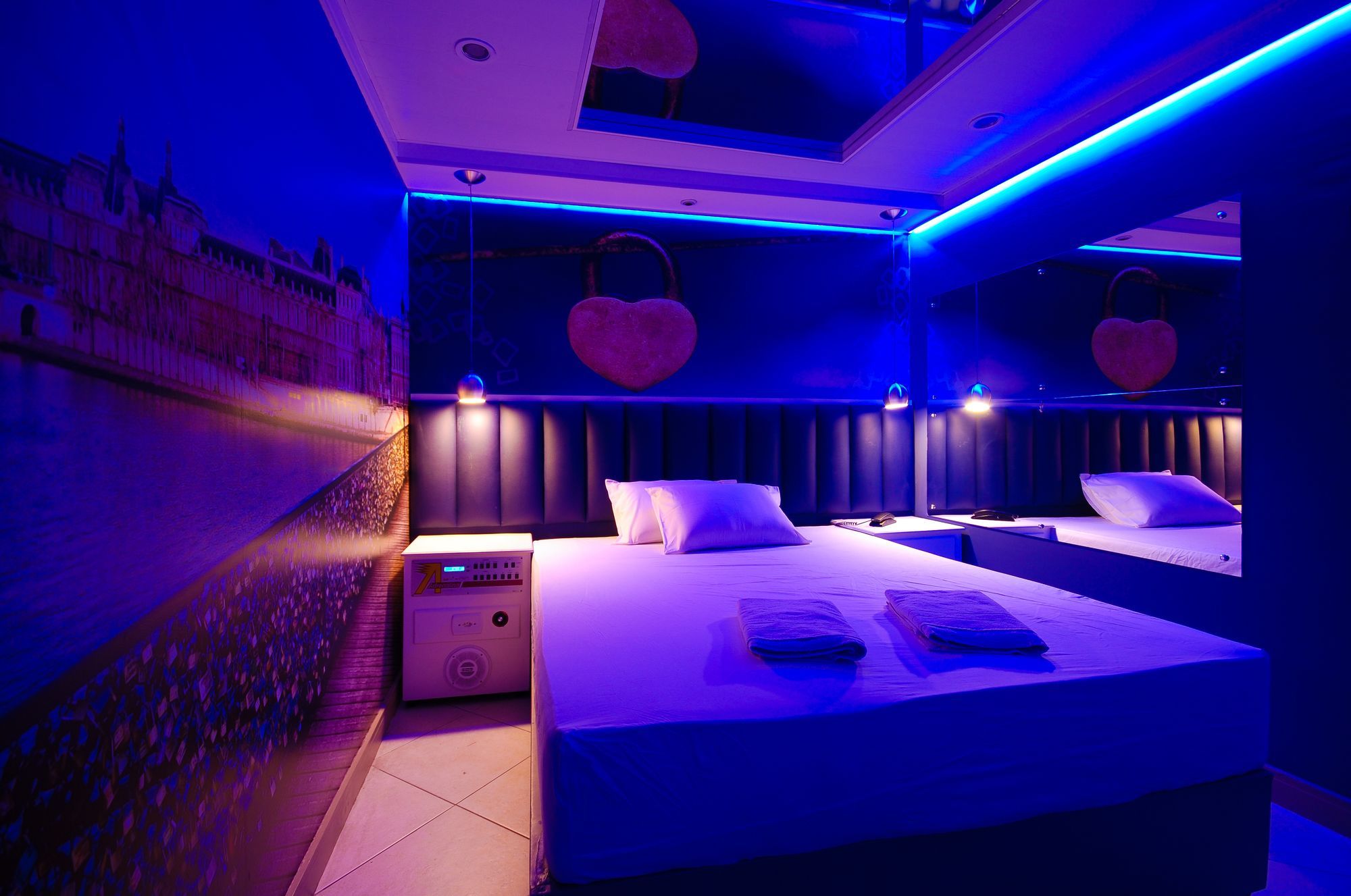 Quarto moderno com cama grande, mesas de cabeceira e aquecedor fixado na parede.