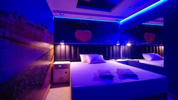Quarto moderno com cama grande, mesas de cabeceira e aquecedor fixado na parede.