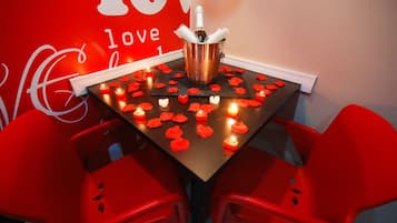 Uma mesa com garrafa de champanhe, velas e pétalas de rosa.