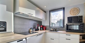 Eine moderne Küche mit integriertem Mikrowellenherd, einer Kaffeemaschine und einem großen Fenster.