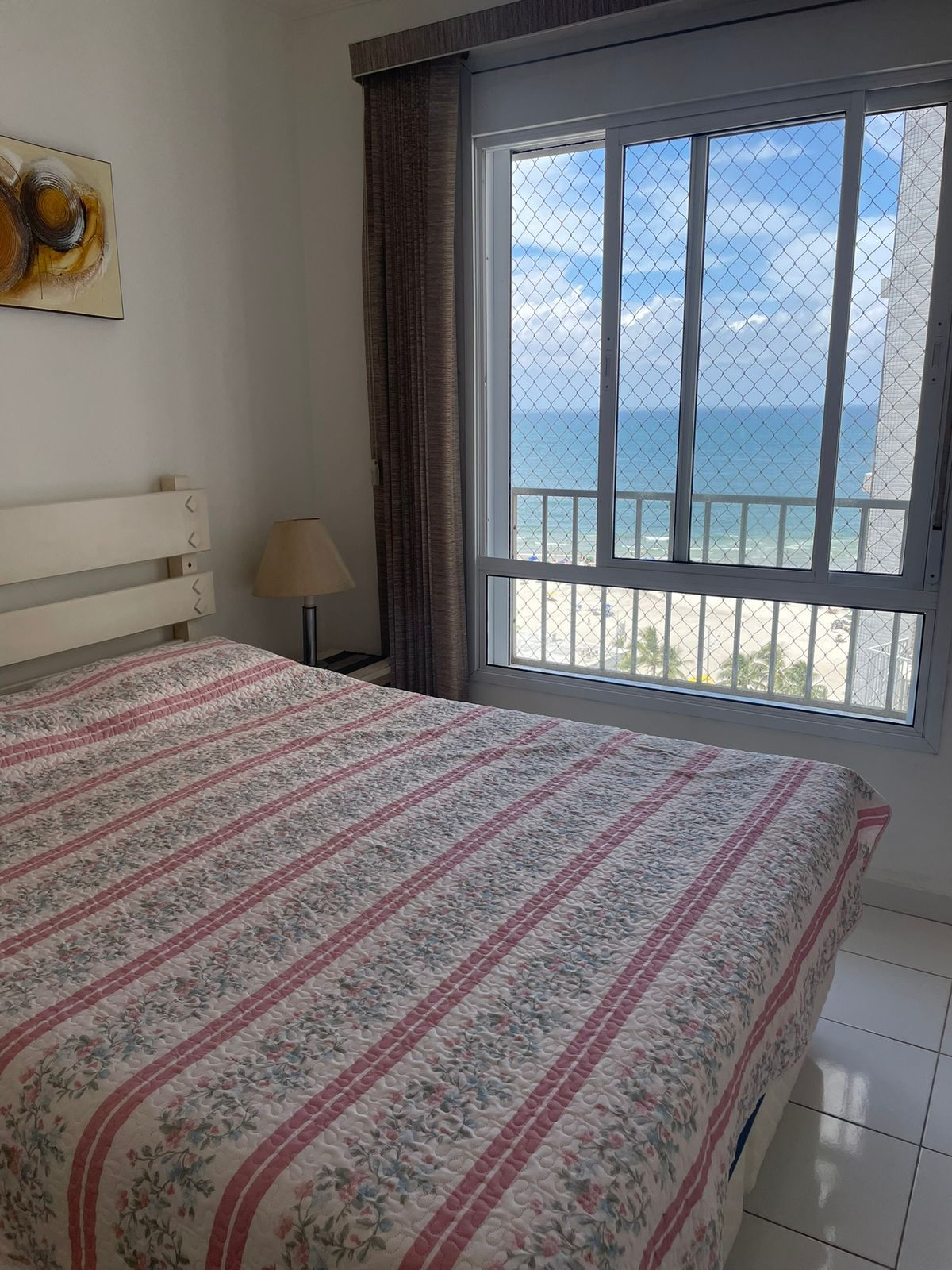 Une chambre à coucher avec un lit, une fenêtre donnant sur la mer et une lampe.