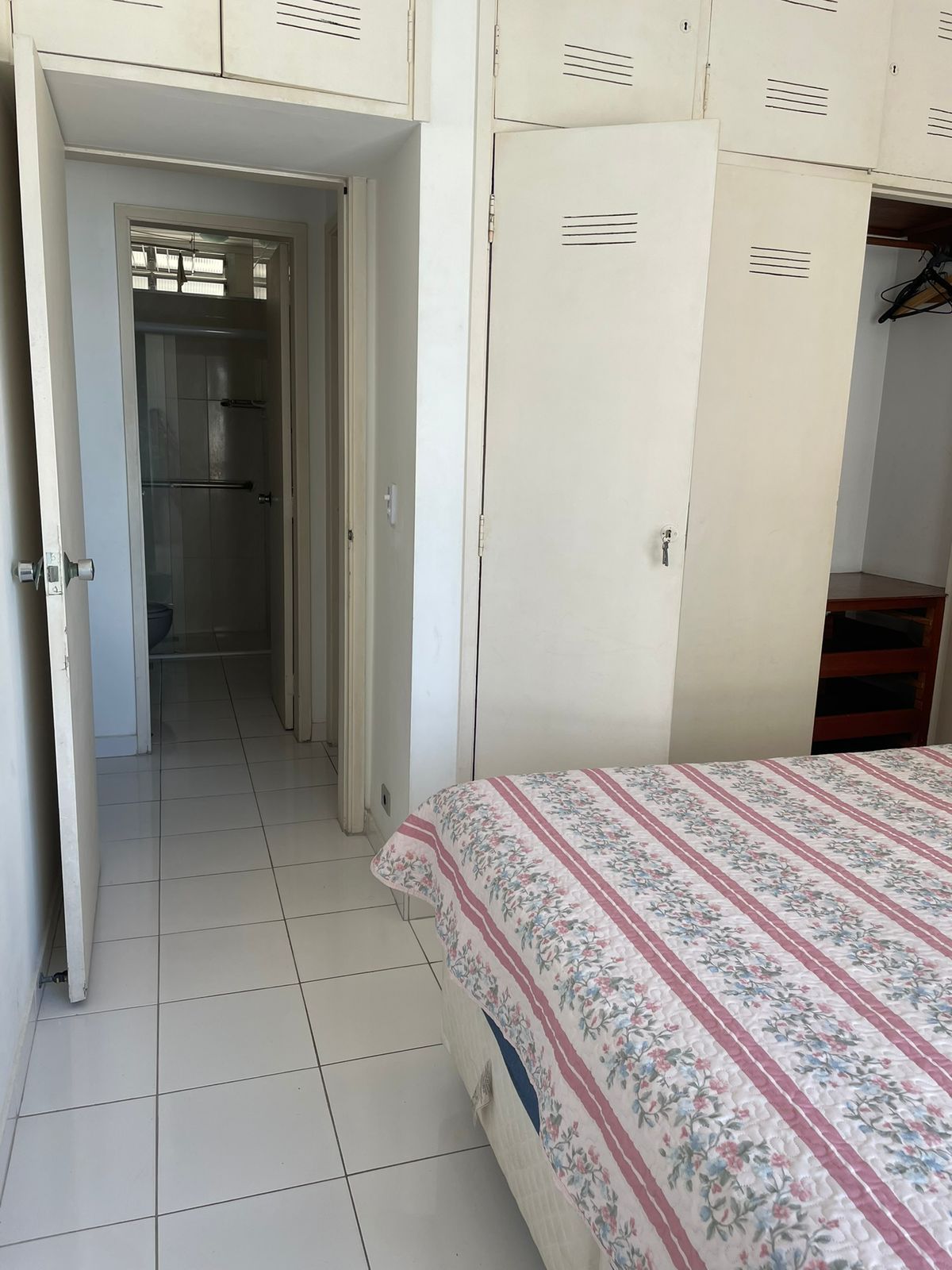 A bedroom with a bed, a wardrobe, and a bathroom.