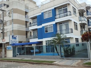 Un edificio residencial de varios pisos con balcones, una piscina y un letrero que indica que es propiedad residencial.