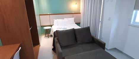 A hotel room with a bed, a sofa, a desk, and a wardrobe.