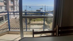 Ein Balkon mit Blick auf das Meer und ein Gebäude im Hintergrund.