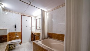 A bathroom with a toilet, sink, and bathtub. - L M B Hotel (Jaipur)