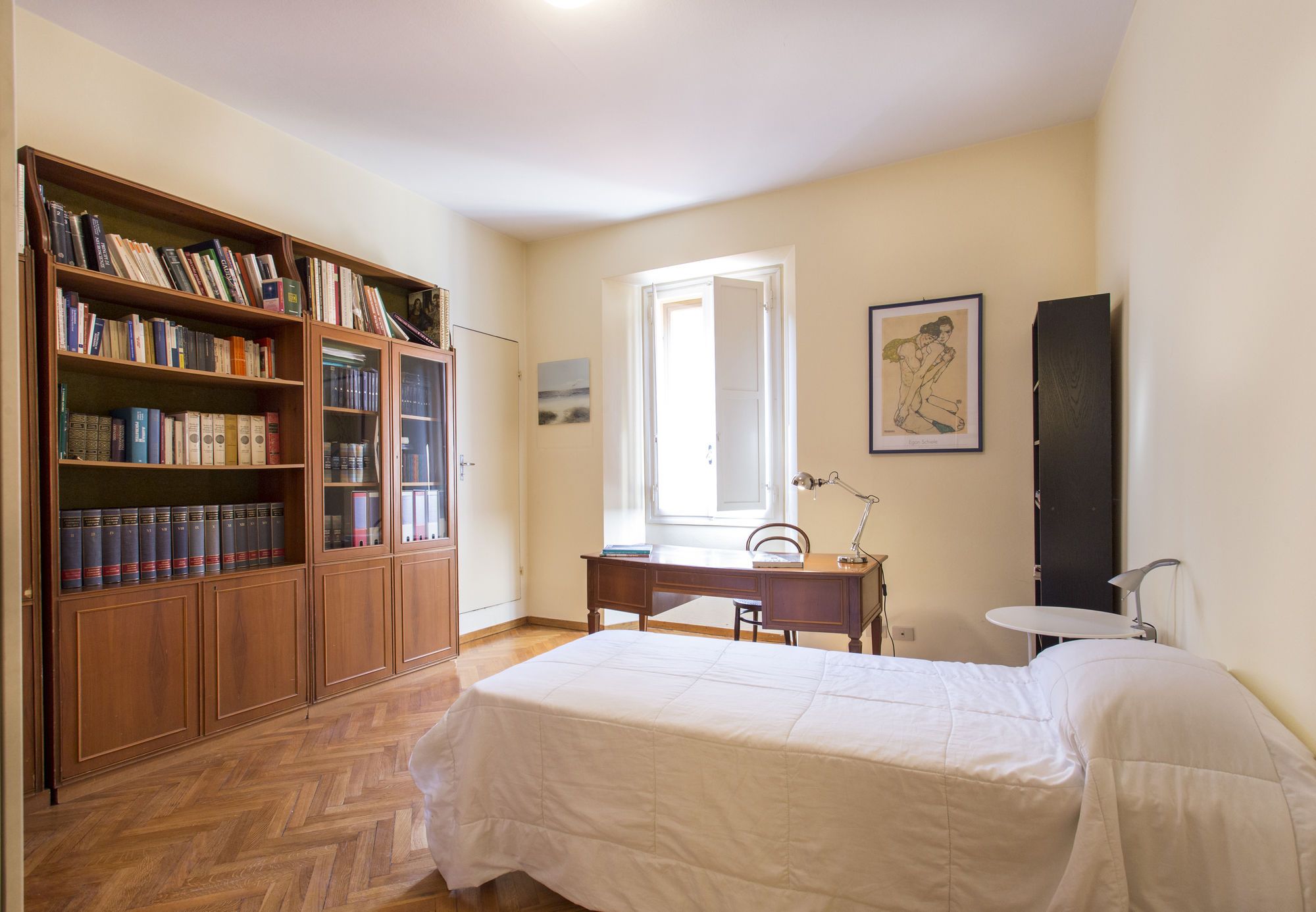 A bedroom with a bed, a desk, a chair, a bookshelf, and a window.