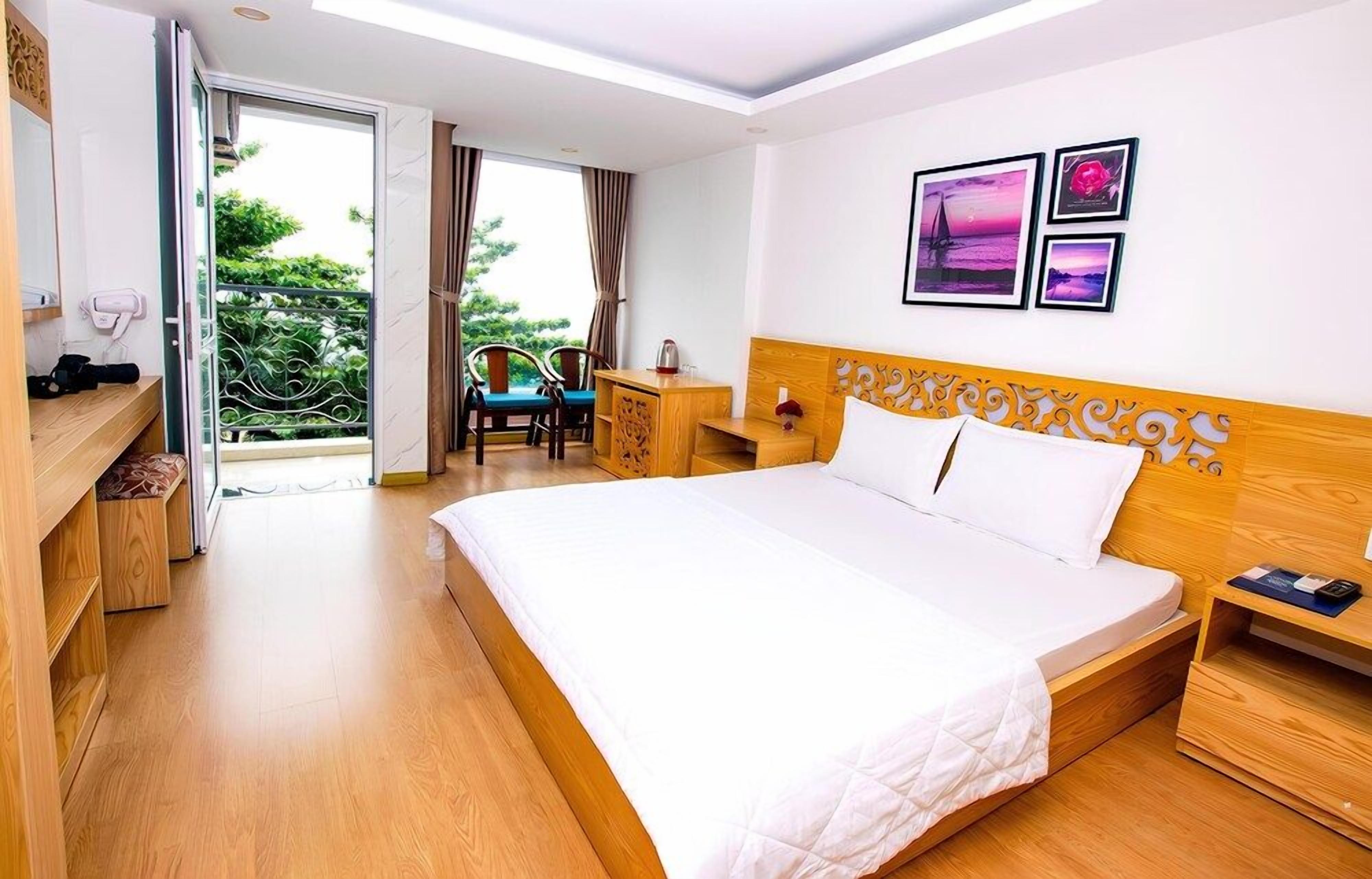 Une chambre d’hôtel avec un grand lit, un bureau, une chaise et un balcon donnant sur un espace verdoyant.