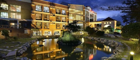 A multi-story hotel with a reflective pond and stone pathway.