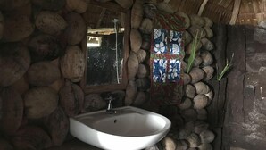 Ein rustikales Badezimmer mit einer Steinwand, einem weißen Waschbecken und einem Spiegel.