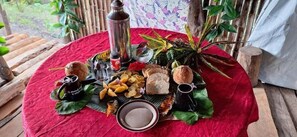 A table set with various food items and a thermos on a red tablecloth. - Tanna Lava View Bungalows (Tanna Island)