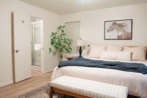 A bedroom with a bed, bedside table, lamp, and a wall-mounted picture. - Spacious 4-bedroom house in Historic College Station near TAMU (College Station)