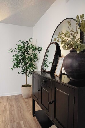 A room with a wooden floor, a dark-colored cabinet, a mirror, and a potted plant. - Spacious 4-bedroom house in Historic College Station near TAMU (College Station)