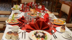 A dining table set with various dishes, including a roasted chicken, salads, and bread rolls. - Dib Anbessa Hotel (Bahir Dar)