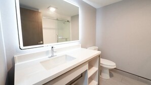 A bathroom with a white sink, a mirror, and a toilet. - King Bed Harbor View (Fiarhaven)