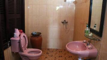 A bathroom with a pink toilet, a pink sink, and a shower.
