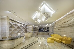 A modern lobby with a reception desk, geometric wall patterns, and a staircase leading to upper floors. - Attide Boutique Hotel (Bengaluru)