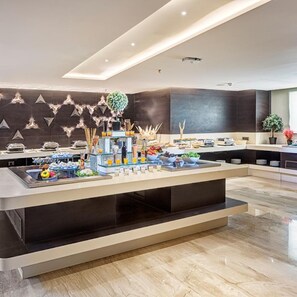 A modern hotel lobby with a central buffet area featuring a variety of food and drink options. - Attide Boutique Hotel (Bengaluru)