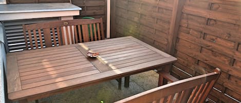 A wooden table and chairs in a covered outdoor area with a wooden fence.