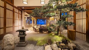 Un interior japonés tradicional con comedor, un bonsái y un jardín de rocas.