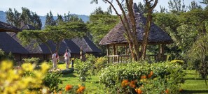 A rural setting with thatched-roof huts, a gazebo, and lush greenery. - Neptune Ngorongoro Luxury Lodge - All Inclusive (Karatu)