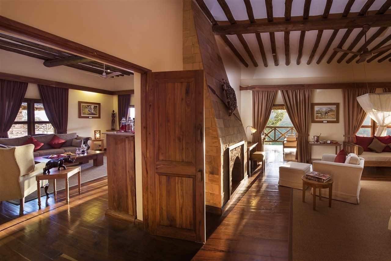 A spacious living area with a fireplace, wooden beams, and a view through large windows.