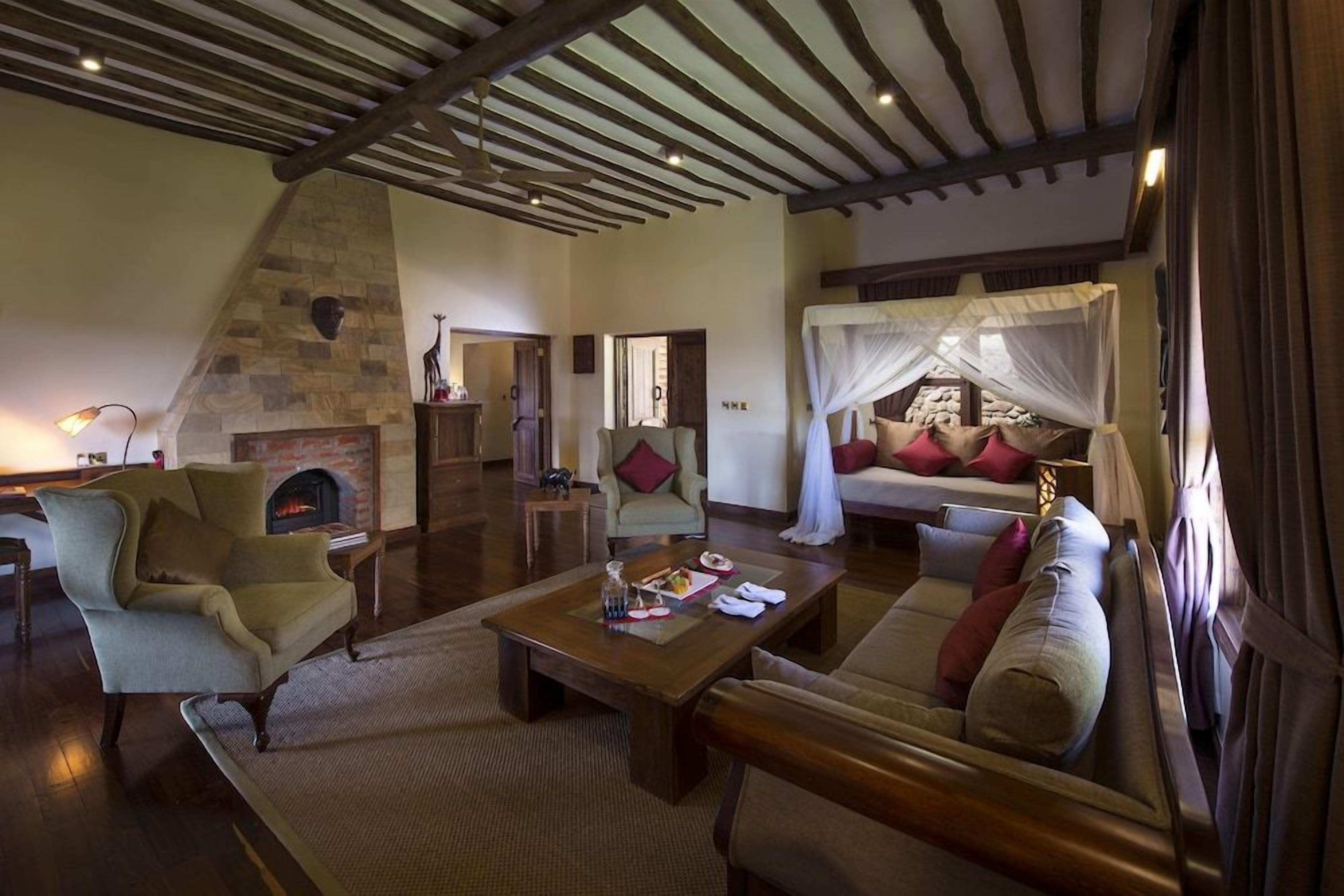 A spacious living room with a stone fireplace, a comfortable sofa set, a coffee table, and a high ceiling with exposed beams.
