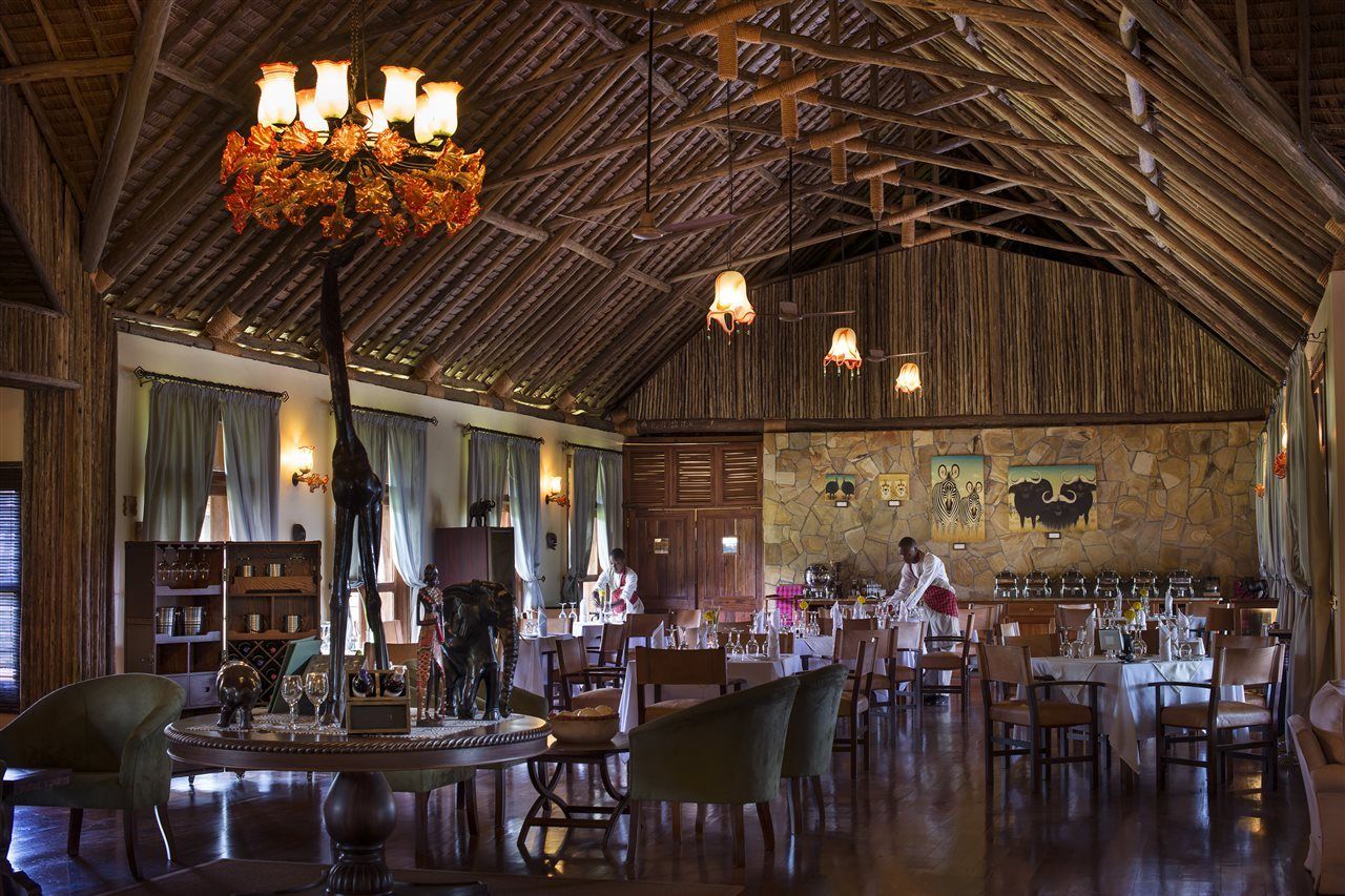 A spacious dining area with high ceilings and exposed wooden beams, featuring a central chandelier and multiple hanging light fixtures.