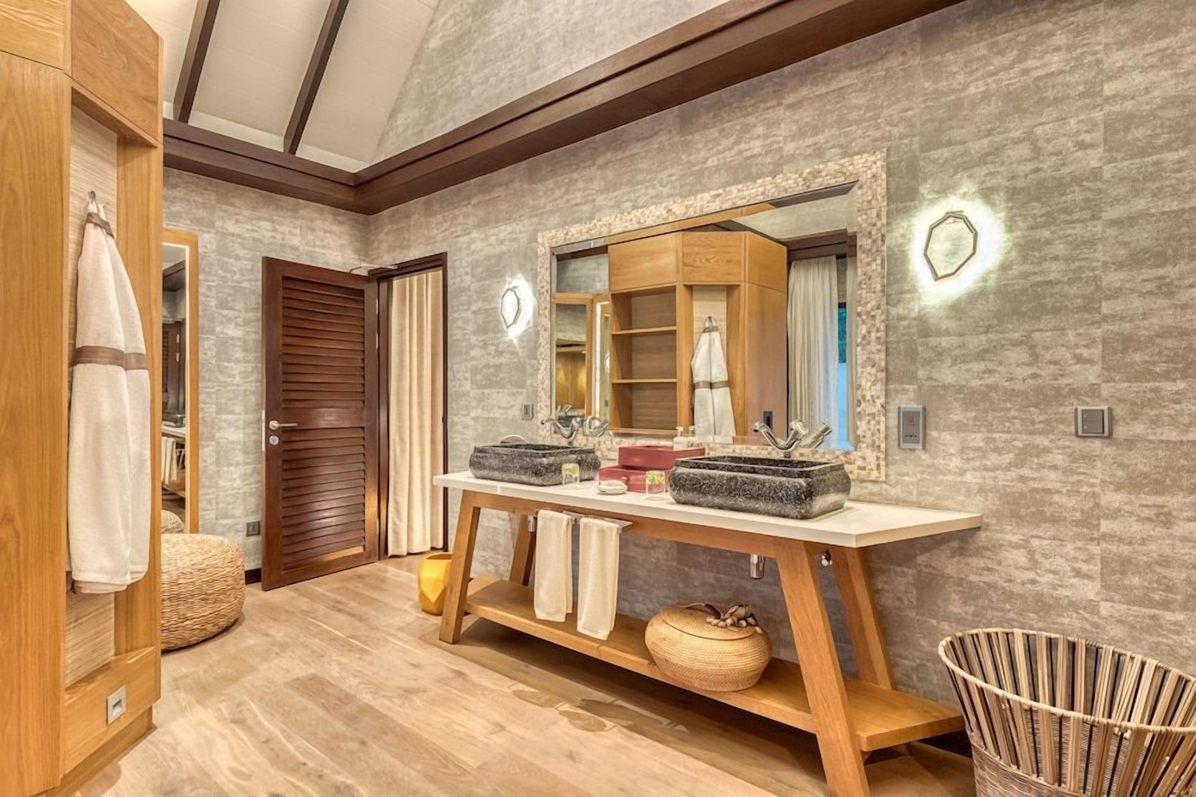 A bathroom with a wooden vanity, a large mirror, and a modern sink.