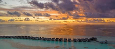 An overwater resort with multiple bungalow-style accommodations connected by walkways.