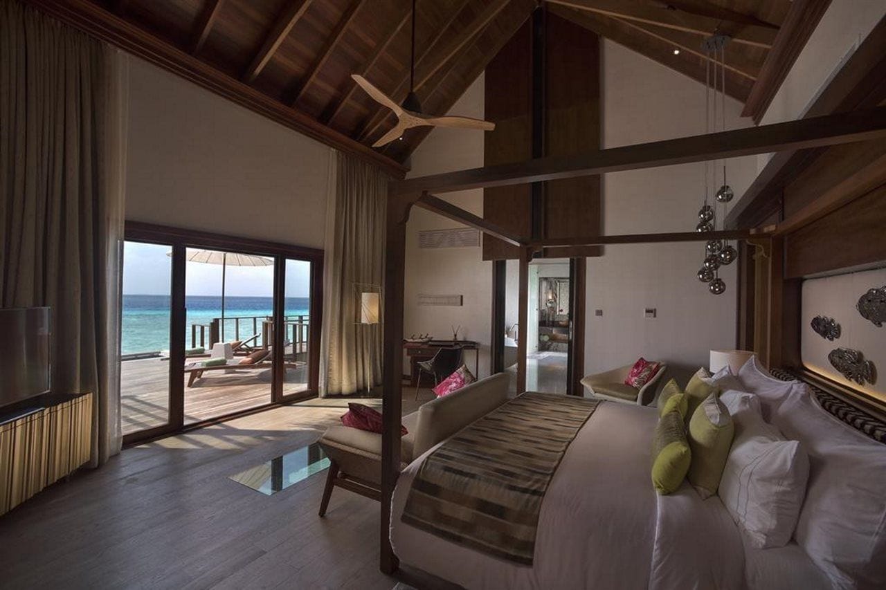 A spacious bedroom with a large bed, a view of the ocean, and a balcony.