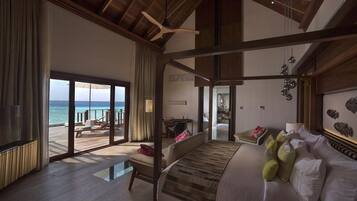 A spacious bedroom with a large bed, a view of the ocean, and a balcony.