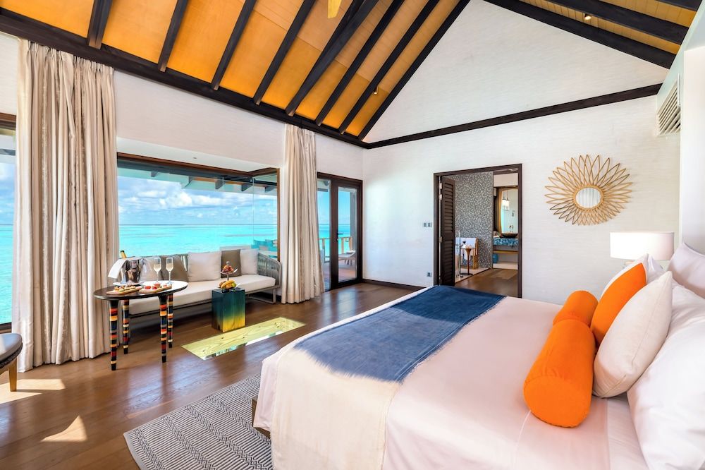 A modern bedroom with a large bed, a view of the sea, and a balcony.