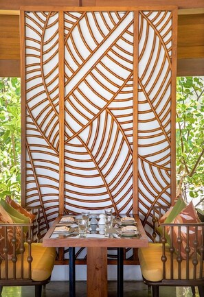 A dining area with a table set for two, surrounded by chairs with cushioned seats. - Ozen Life Maadhoo Resort (Maadhoo)