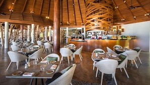 A spacious indoor dining area with high ceilings and wooden beams, featuring tables and chairs arranged for guests. - Ozen Life Maadhoo Resort (Maadhoo)