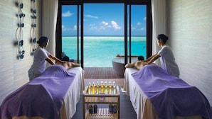 A room with two massage tables, a small table with bottles, and a view of the ocean. - Ozen Life Maadhoo Resort (Maadhoo)