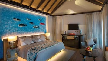 Habitación de hotel con una cama grande, un televisor de pantalla plana, una mesa de comedor y una pared con un diseño abstracto azul.
