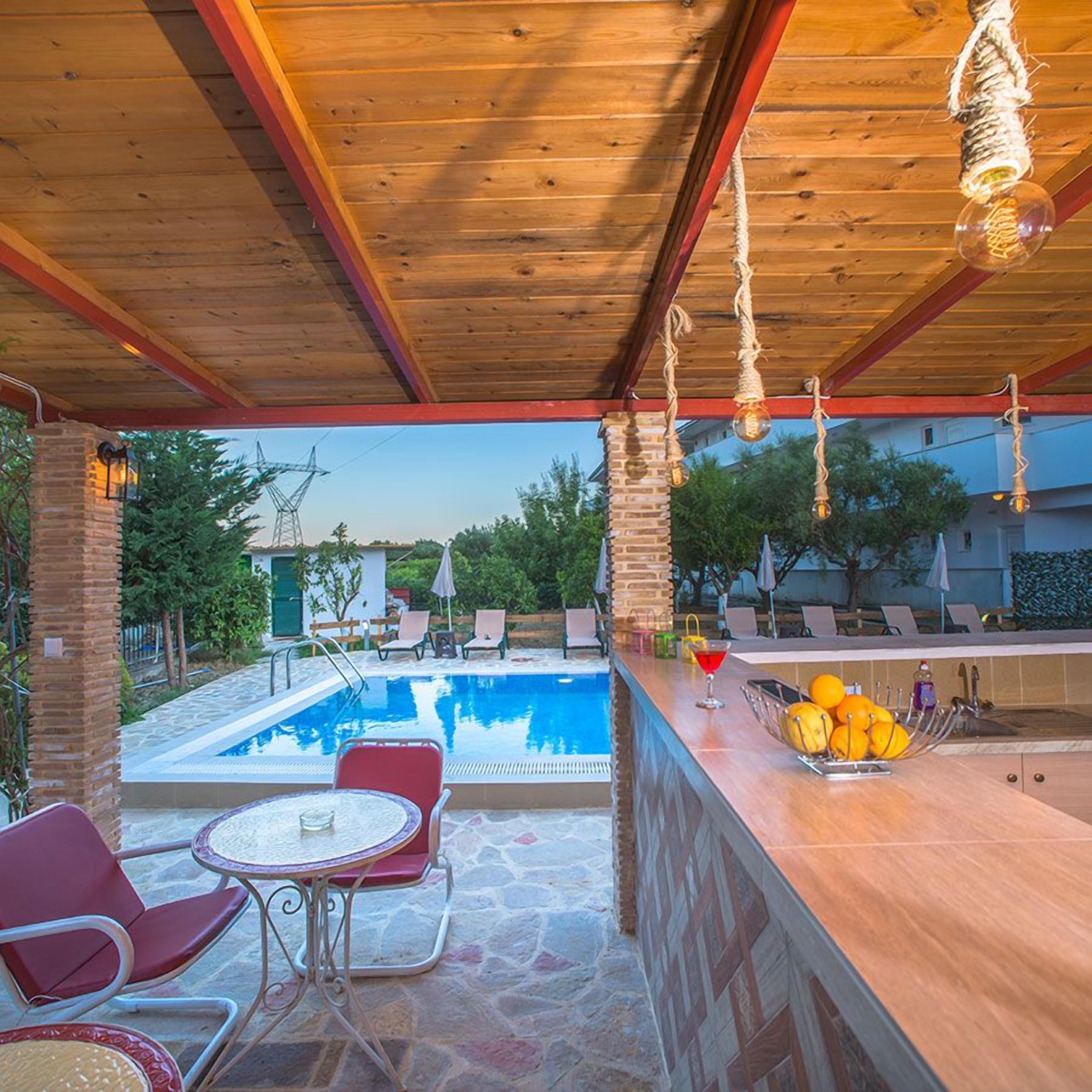 Zona de piscina exterior con bar y asientos.