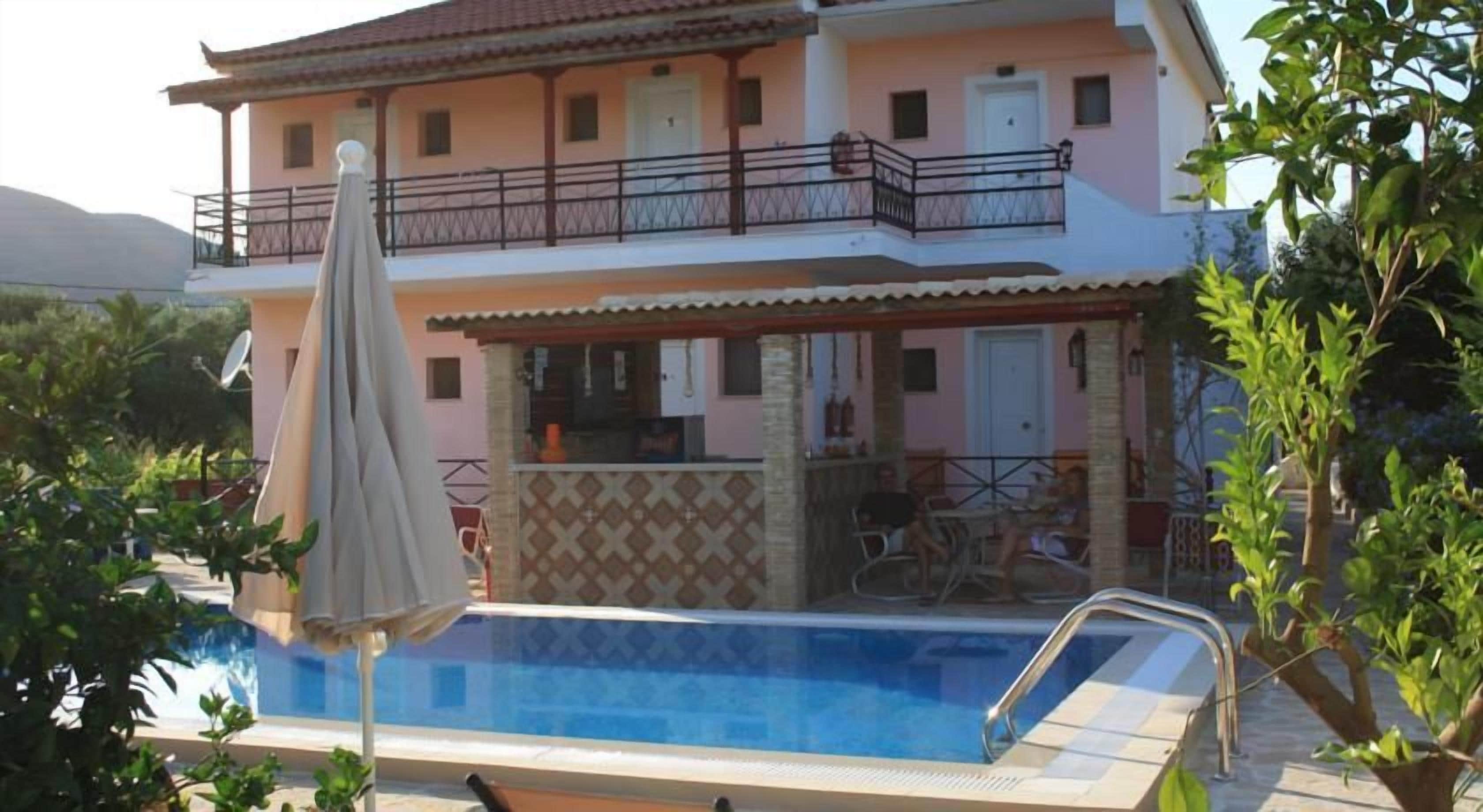 A two-story building with a swimming pool, outdoor seating, and a balcony.