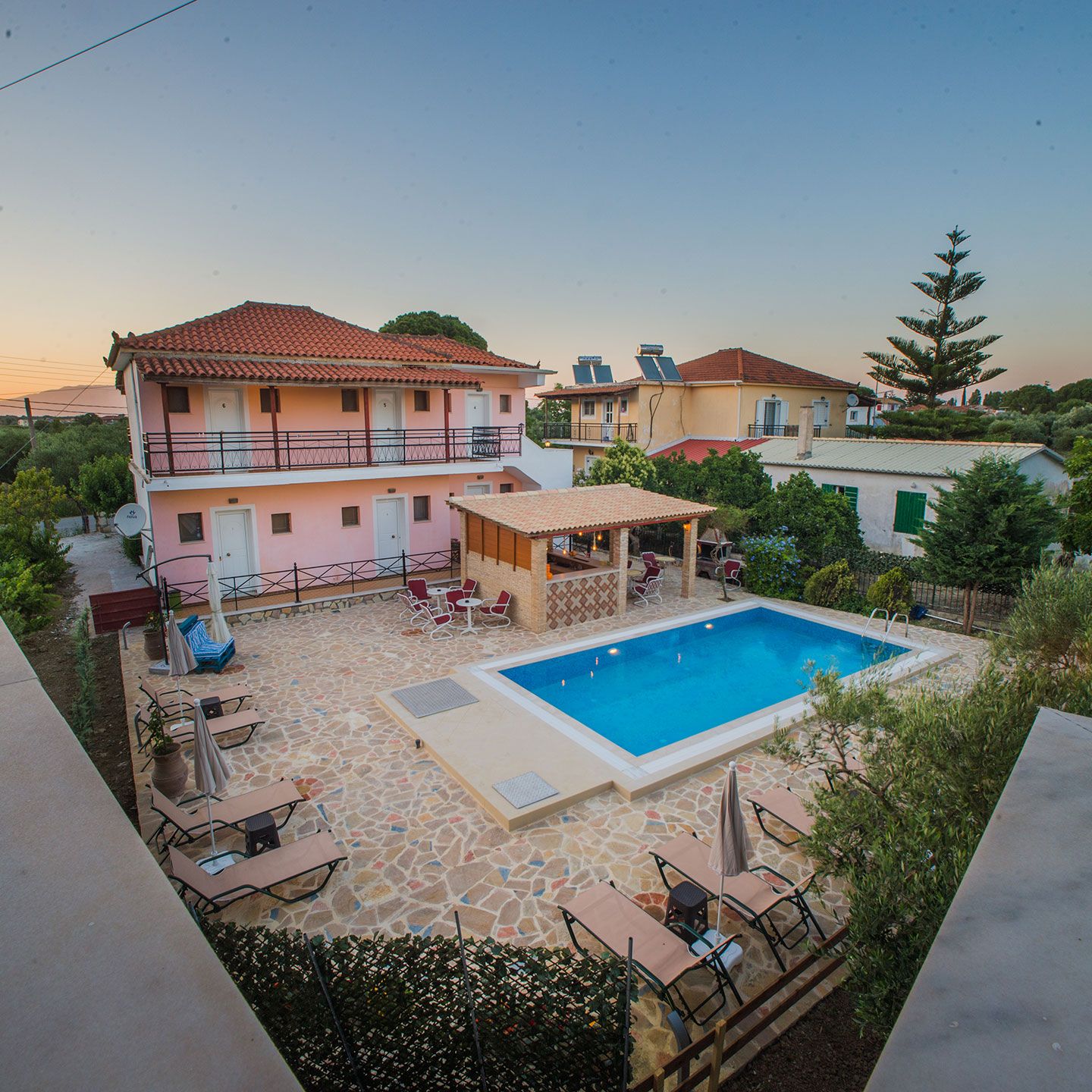 A two-story house with a swimming pool, outdoor seating, and a garden.