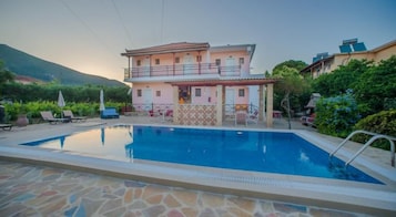 Uma casa de dois andares com piscina em frente.