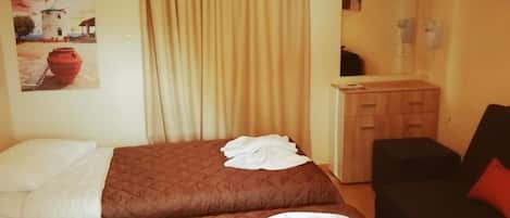 A hotel room with two beds, a wooden dresser, a mirror, and a painting on the wall.